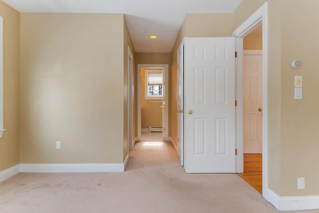 hallway featuring light carpet and baseboards