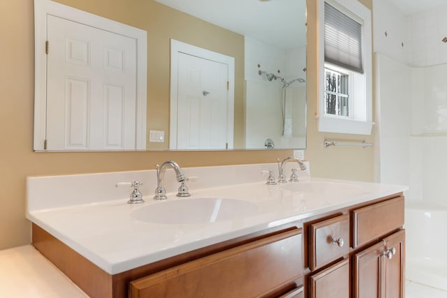 full bathroom featuring double vanity, a shower, and a sink