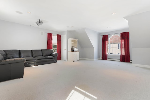 living area featuring a baseboard heating unit, light colored carpet, and baseboards