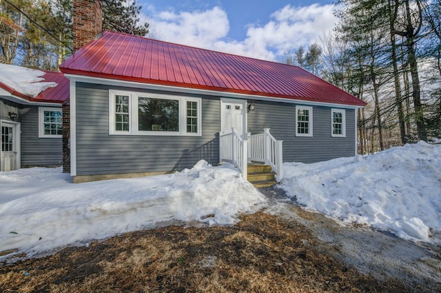 view of front of house featuring metal roof and a chimney