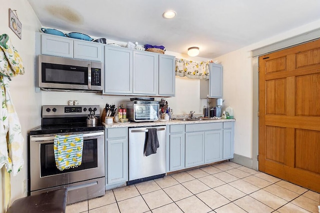 kitchen with sink, light tile patterned floors, and stainless steel appliances