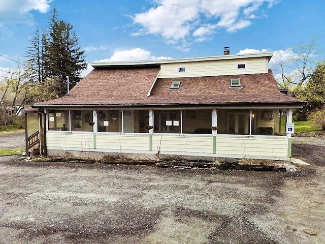 view of front of home featuring a sunroom, a shingled roof, and a chimney