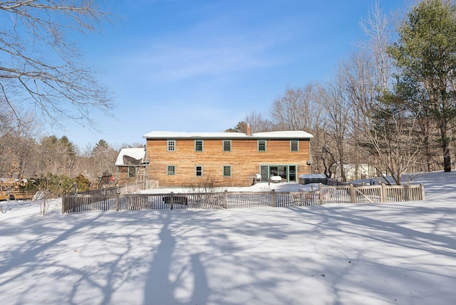 snow covered rear of property featuring fence