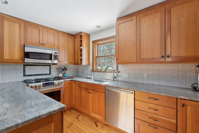 kitchen featuring light stone counters, a sink, appliances with stainless steel finishes, backsplash, and open shelves