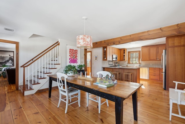 dining space with light wood-style flooring, stairs, and visible vents