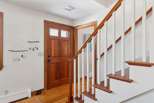 foyer entrance with light wood-style flooring, stairs, and baseboard heating