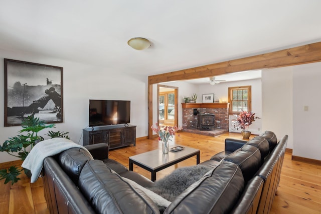 living room featuring a wood stove, light wood finished floors, and baseboards