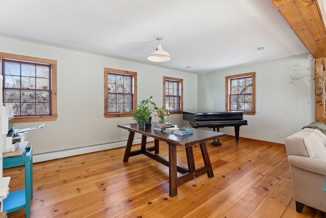 office area with baseboard heating, baseboards, and light wood finished floors