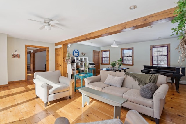 living area featuring light wood finished floors, a ceiling fan, baseboards, and beamed ceiling