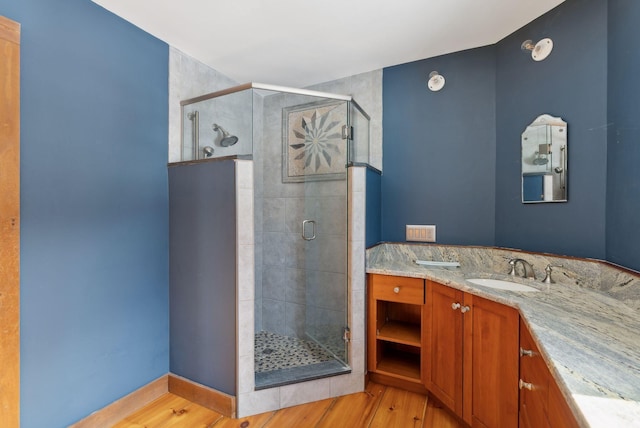 bathroom with a stall shower, wood finished floors, and vanity