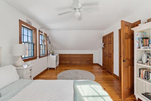 bedroom with lofted ceiling, light wood-style floors, baseboards, and a ceiling fan