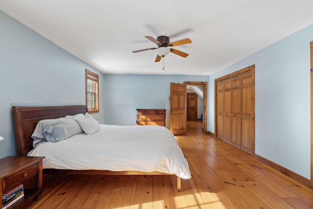 bedroom featuring a ceiling fan, a closet, light wood-style flooring, and baseboards