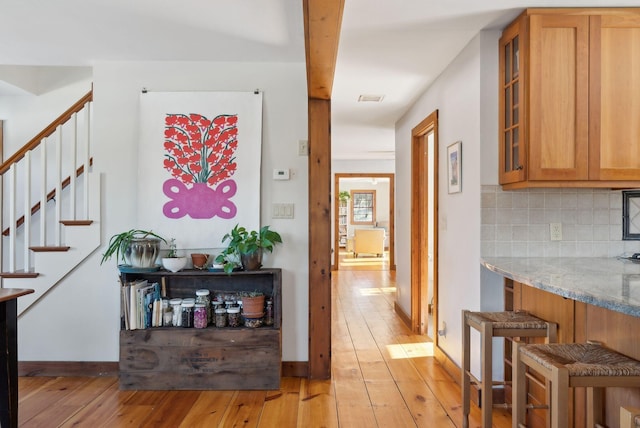 hall with baseboards, stairway, and light wood-style floors