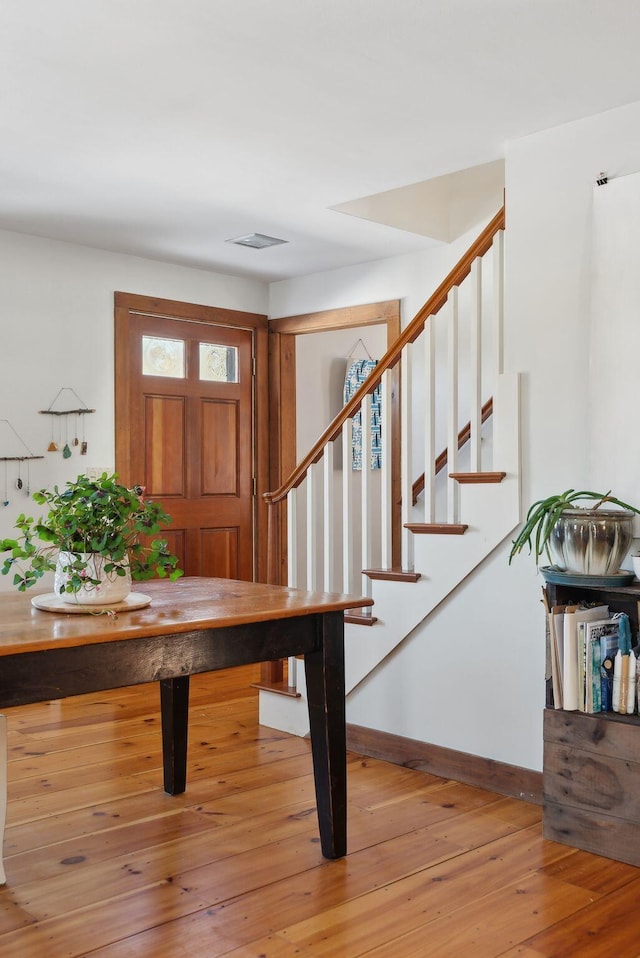 foyer entrance with stairway, visible vents, light wood-style flooring, and baseboards