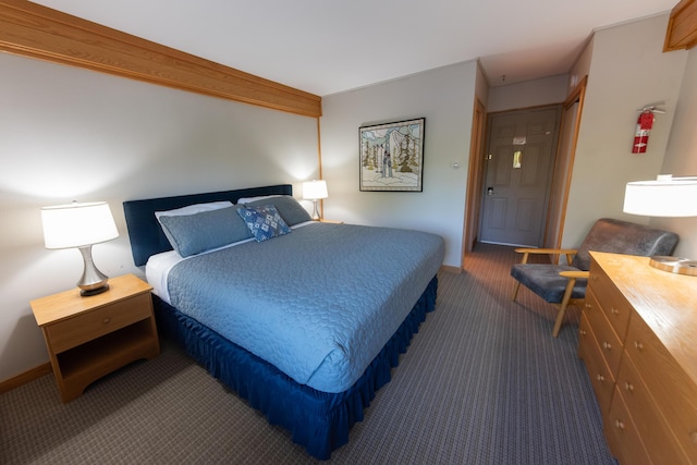 bedroom featuring baseboards and dark carpet