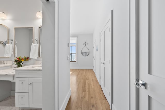 corridor with light wood-type flooring and baseboards