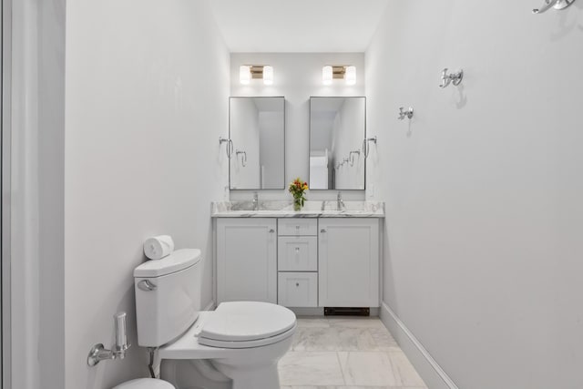 full bathroom featuring marble finish floor, double vanity, toilet, a sink, and baseboards