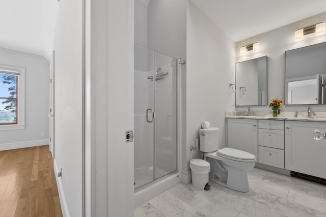 bathroom featuring double vanity, toilet, a stall shower, a sink, and baseboards