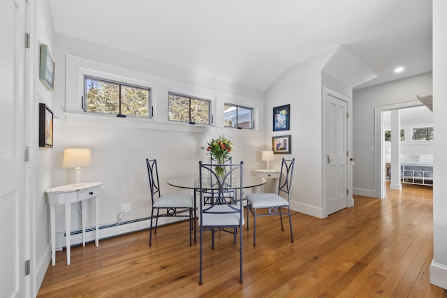 dining space with a baseboard heating unit, plenty of natural light, and light wood-style floors