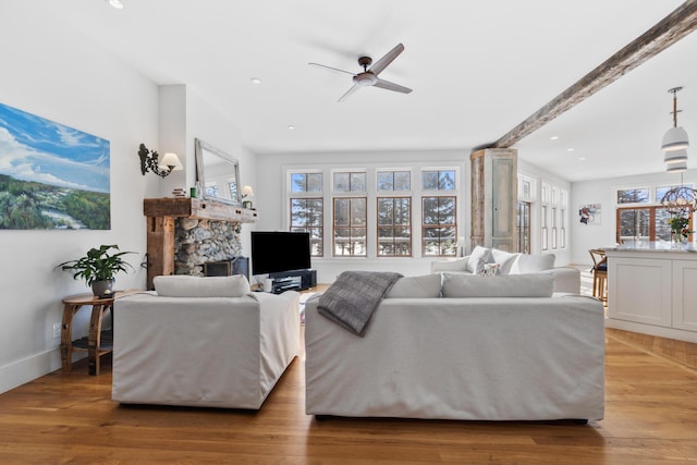 living room featuring baseboards, beam ceiling, a ceiling fan, and wood finished floors