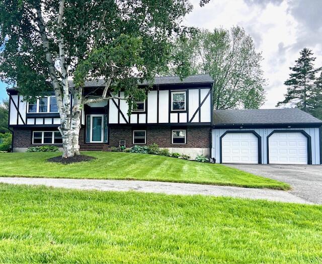 view of front of house with an attached garage, aphalt driveway, and a front yard