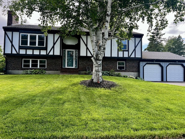 tudor-style house with a garage, a front yard, and a chimney