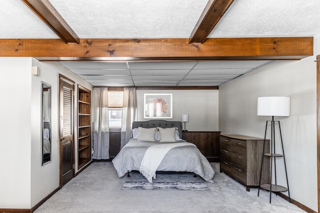 bedroom with light carpet, baseboards, and beamed ceiling