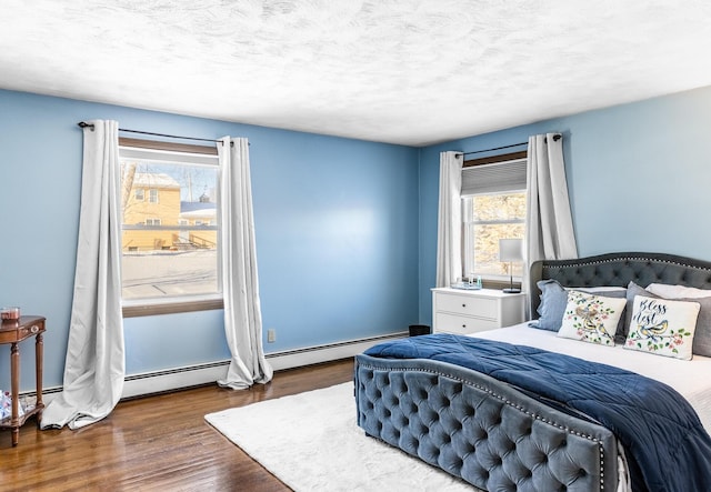 bedroom with dark wood-style floors, a baseboard radiator, multiple windows, and a textured ceiling