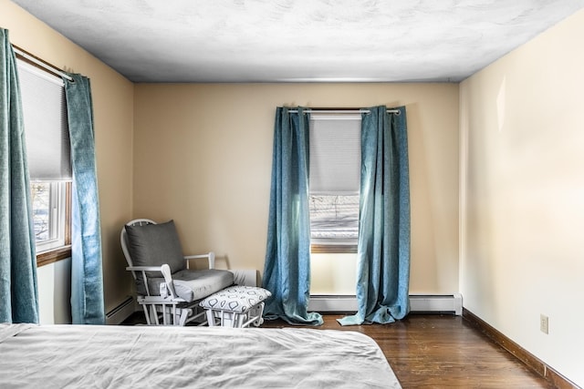 bedroom with dark wood-style flooring, multiple windows, and baseboard heating