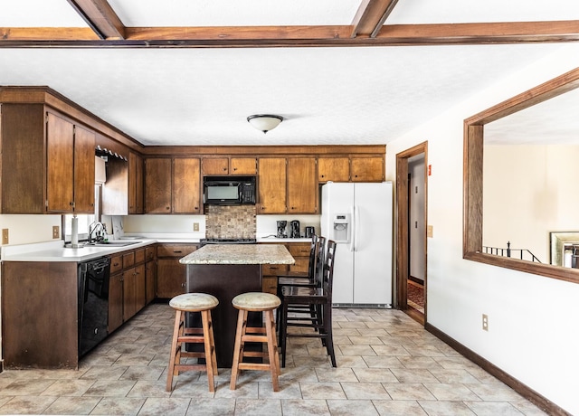 kitchen with a center island, light countertops, a sink, black appliances, and a kitchen bar