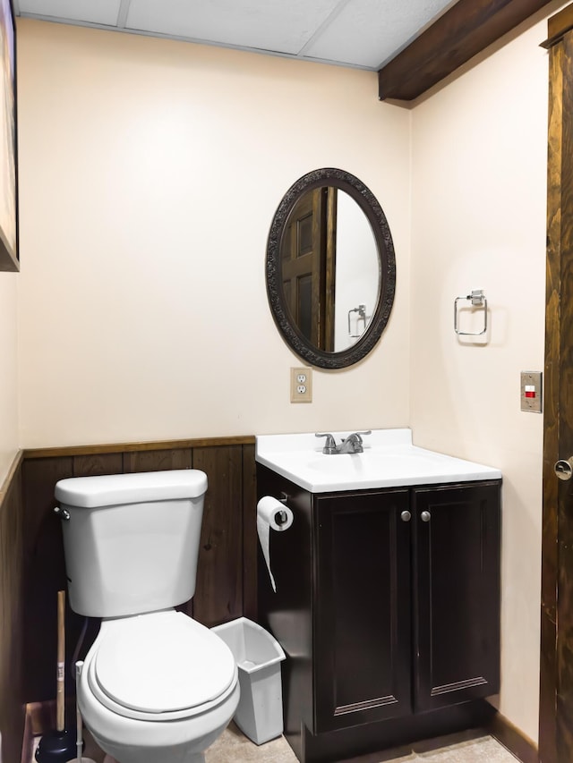 bathroom with a wainscoted wall, a drop ceiling, vanity, and toilet