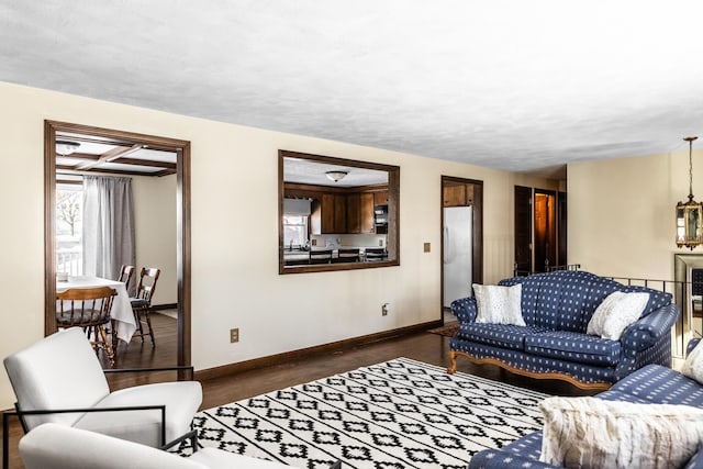 living room featuring dark wood-style floors, beamed ceiling, and baseboards