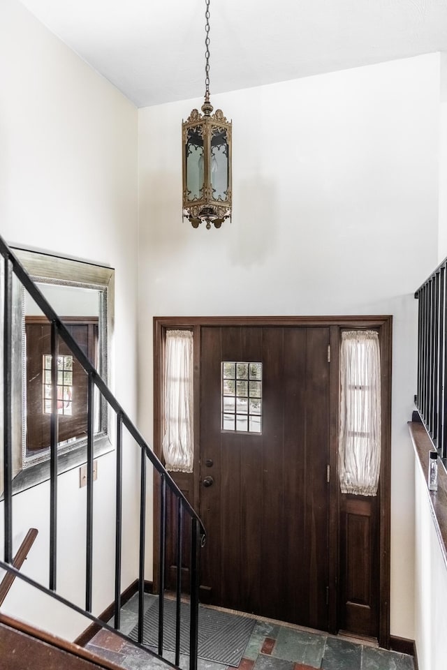 entryway featuring stairs, baseboards, and a notable chandelier