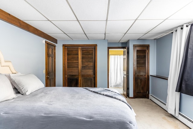 bedroom featuring a paneled ceiling, light colored carpet, and baseboard heating