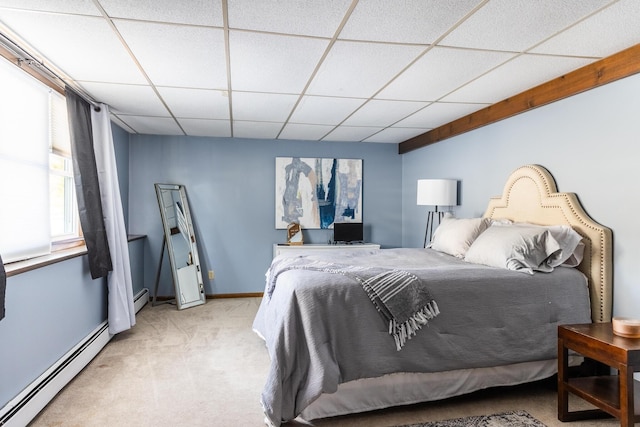 bedroom featuring baseboards, baseboard heating, a drop ceiling, and light colored carpet