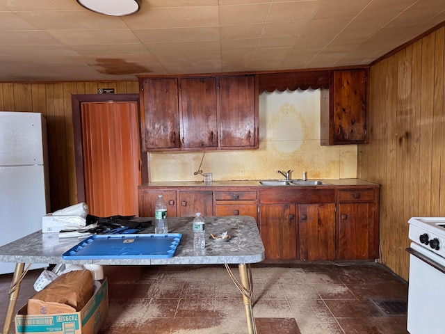 kitchen with white appliances, wooden walls, and a sink