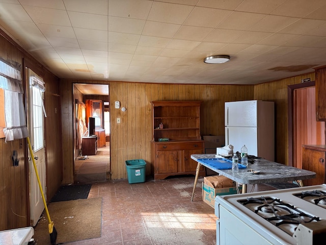 kitchen featuring white appliances, tile patterned floors, and wood walls