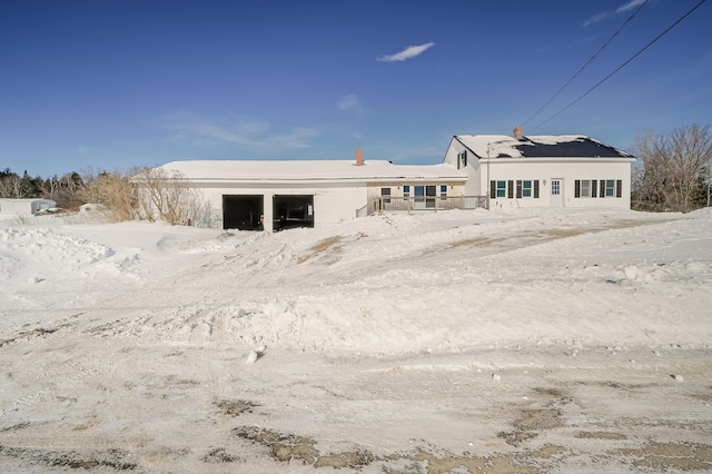 snow covered rear of property with a detached garage