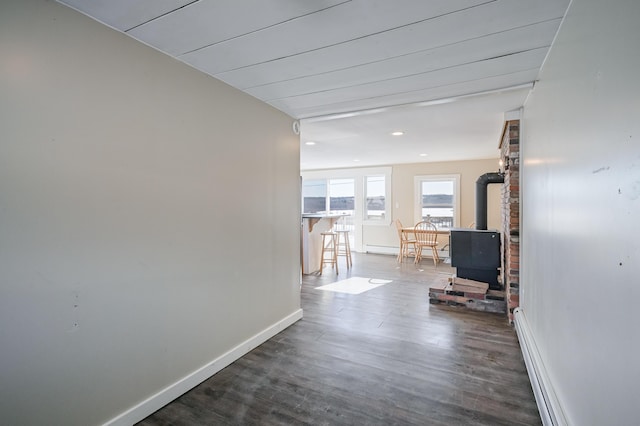 hallway featuring dark wood-type flooring, a baseboard heating unit, and baseboards