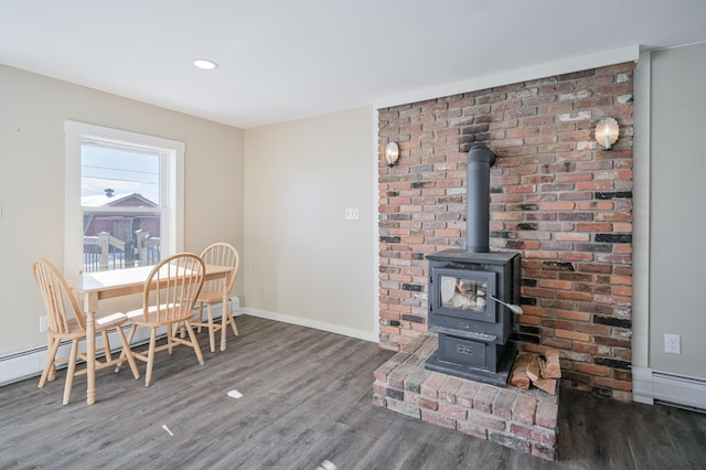 dining area with baseboards, a baseboard radiator, dark wood-style flooring, a wood stove, and recessed lighting