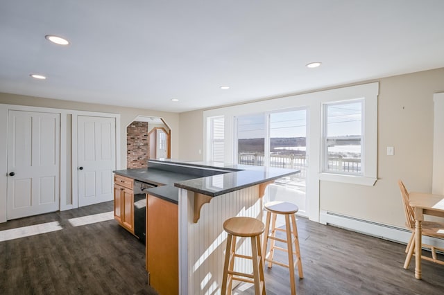 kitchen featuring recessed lighting, dark wood-style flooring, a kitchen island, black dishwasher, and dark countertops