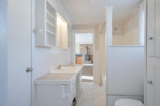 bathroom featuring toilet, a wood stove, marble finish floor, vanity, and shower / washtub combination