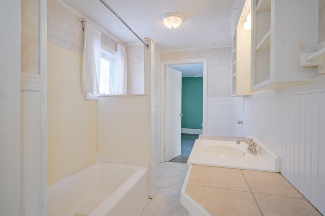 bathroom featuring vanity, a bathtub, crown molding, and wainscoting