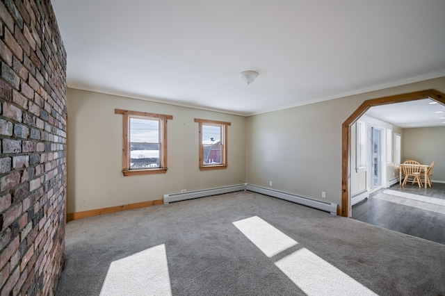 spare room featuring arched walkways, dark carpet, and a baseboard radiator