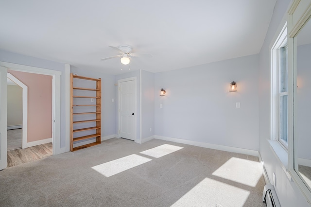 interior space featuring baseboards, a baseboard heating unit, and light colored carpet