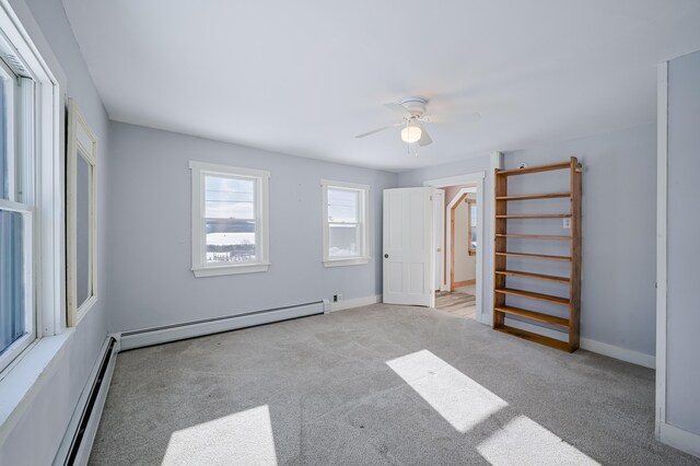 unfurnished bedroom featuring light carpet, a baseboard radiator, baseboards, and ceiling fan