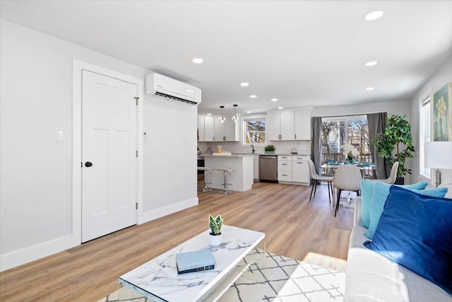 living room featuring baseboards, light wood-type flooring, a wall unit AC, and recessed lighting