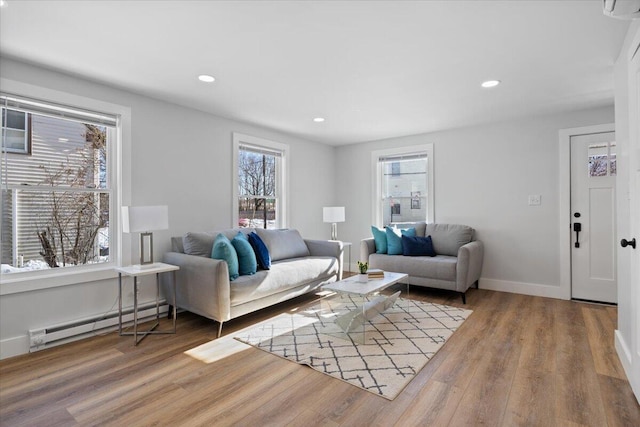 living room featuring a healthy amount of sunlight, baseboard heating, and wood finished floors