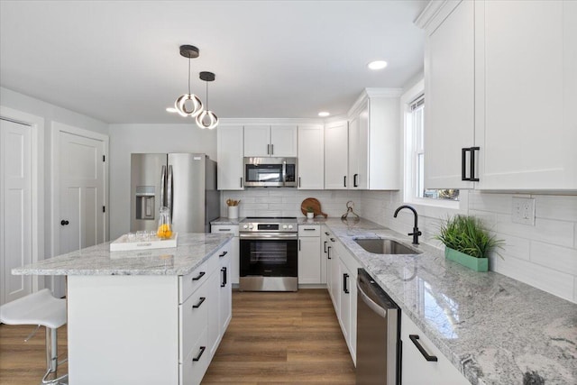 kitchen with a center island, stainless steel appliances, white cabinetry, pendant lighting, and a sink