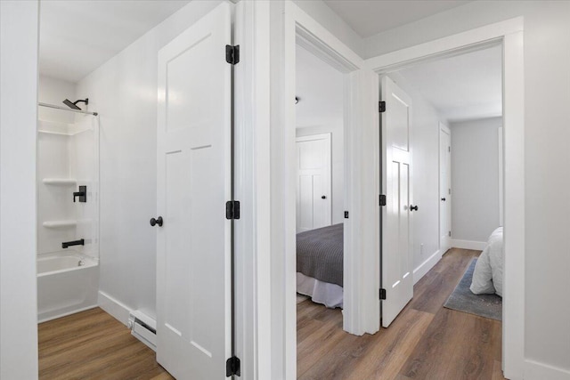 hallway with a baseboard heating unit, dark wood-type flooring, and baseboards